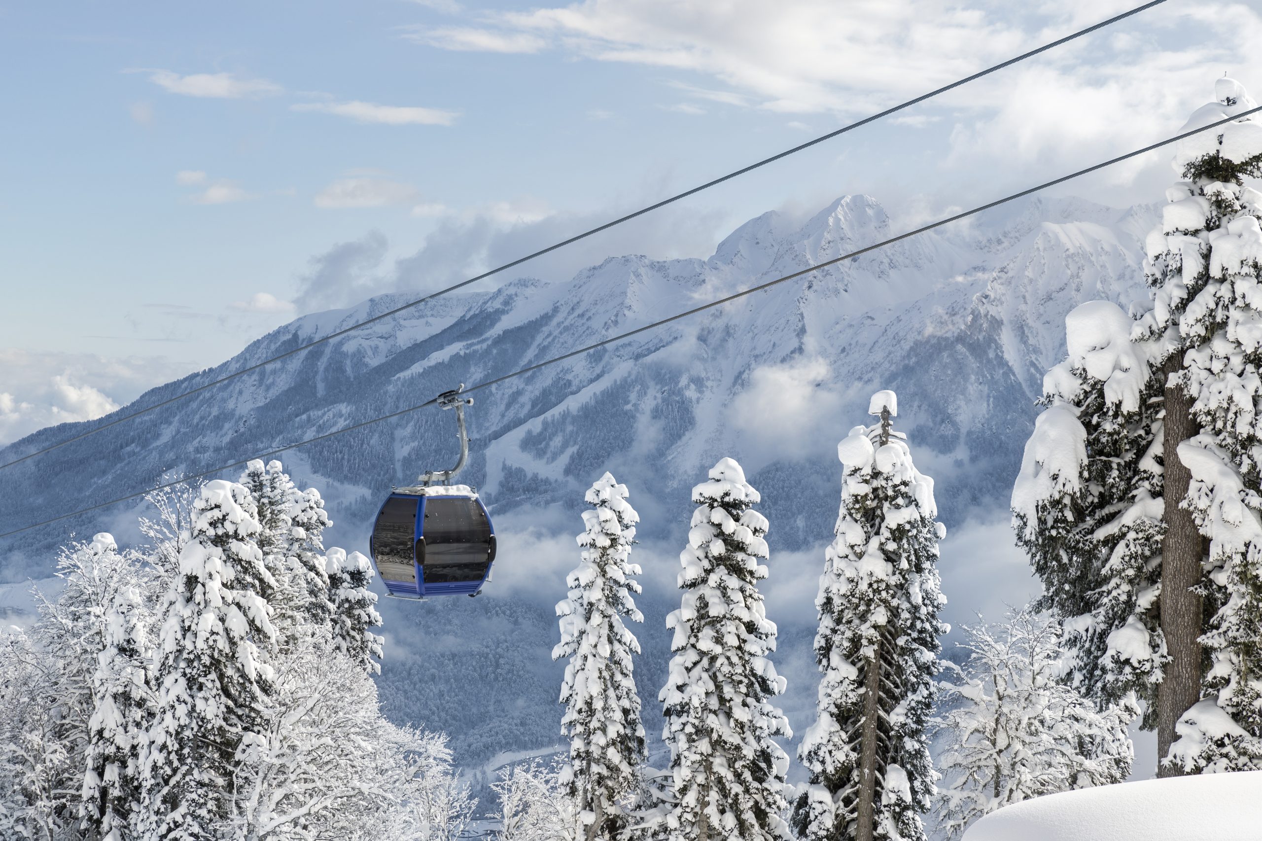 New modern spacious big cabin ski lift gondola against snowcapped forest tree and mountain peaks covered in snow landscape in luxury winter alpine resort. Winter leisure sports, recreation and travel